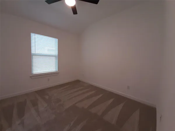 an empty room with a window and a ceiling fan