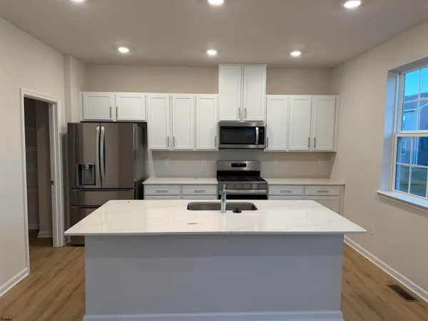 a kitchen with kitchen island a refrigerator sink and stove