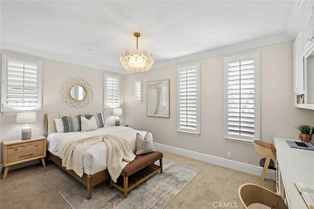 a bedroom with a bed couch chandelier and window