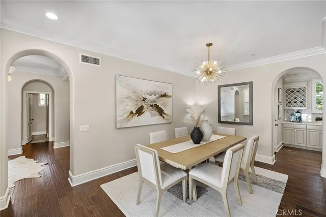 a dining room with wooden floor a chandelier a wooden table and chairs
