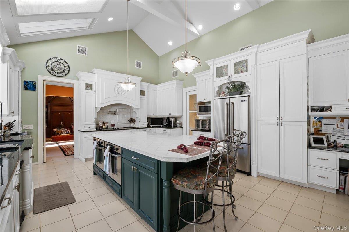45 Coves Run Syosset, NY 11791 - Photo 12 of 43 a kitchen with stainless steel appliances kitchen island granite countertop a table chairs and a refrigerator