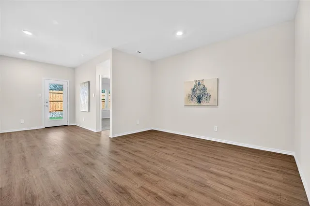 a view of an empty room with wooden floor and closet