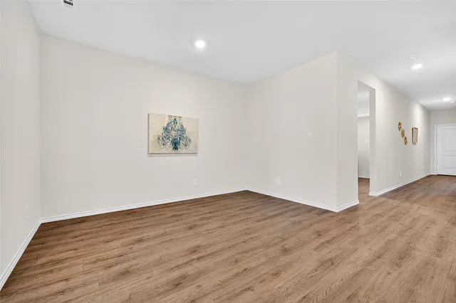 a view of an empty room with wooden floor and window