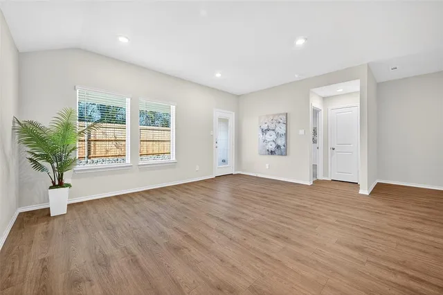 a view of an empty room with window and wooden floor