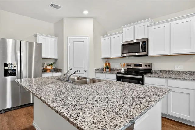 a kitchen with stainless steel appliances granite countertop a sink stove and refrigerator