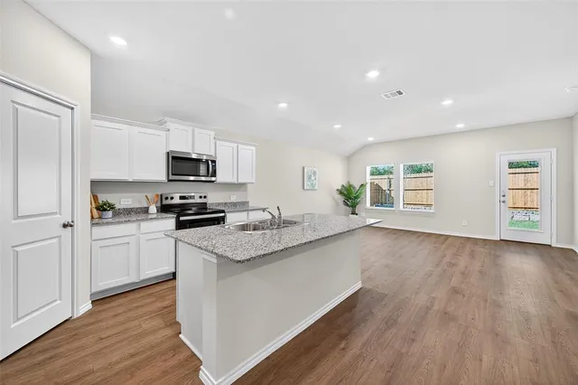 a kitchen with granite countertop appliances cabinets and a wooden floor