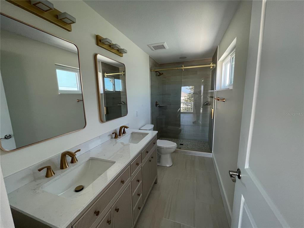 711 Gulf Boulevard Indian Rocks Beach, FL 33785 - Photo 12 of 19 a bathroom with a sink double vanity mirror and toilet
