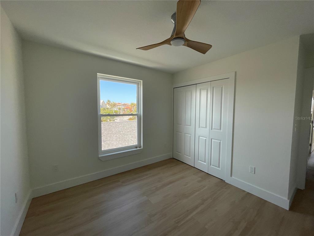 711 Gulf Boulevard Indian Rocks Beach, FL 33785 - Photo 19 of 19 an empty room with wooden floor fan and windows