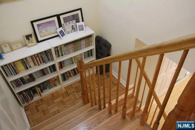 a view of staircase with wooden floor and book shelf