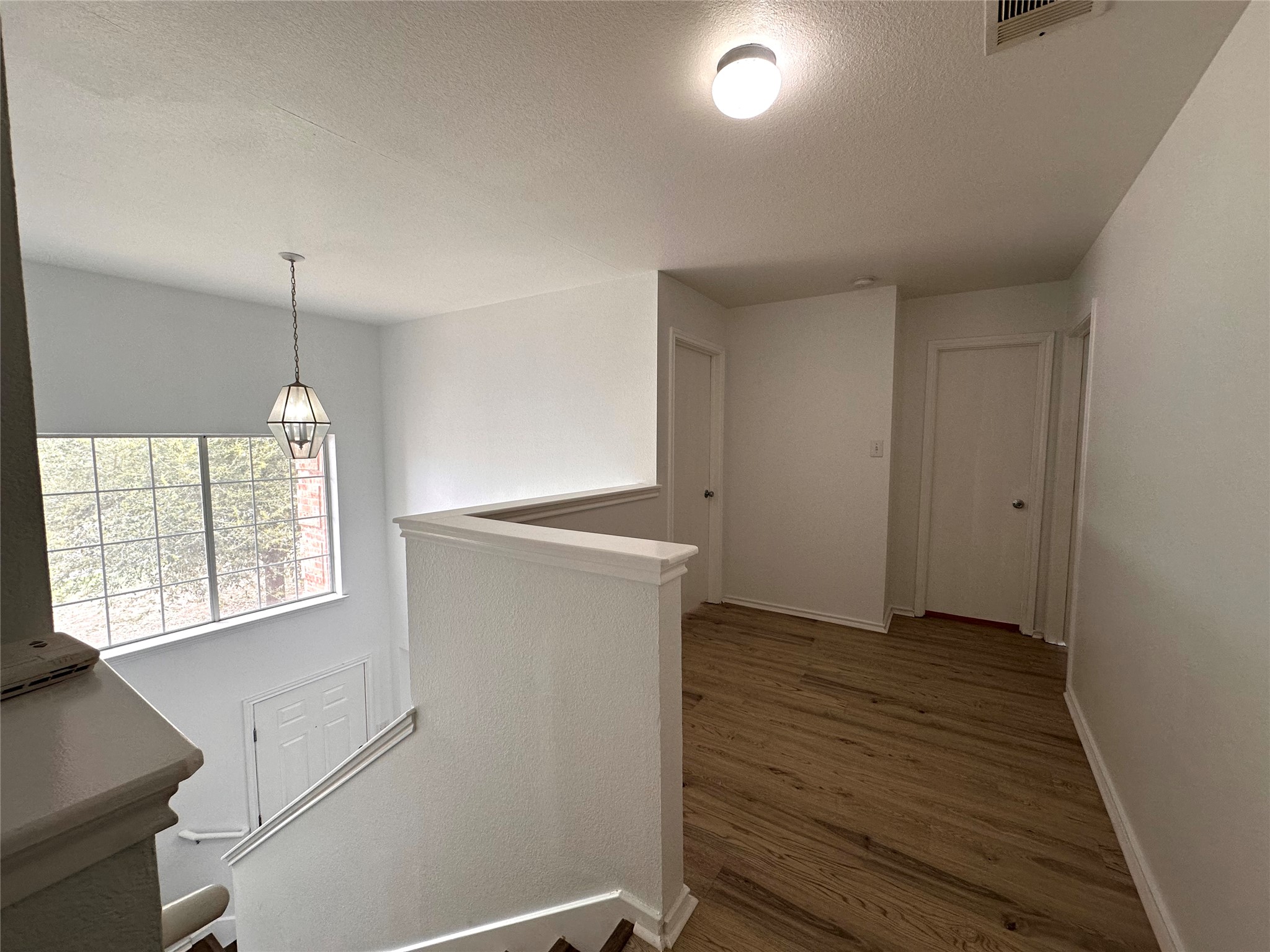 722 Lavaca Loop Elgin, TX 78621 - Photo 9 of 24 Hall featuring a textured ceiling, dark wood-style floors, and an upstairs landing