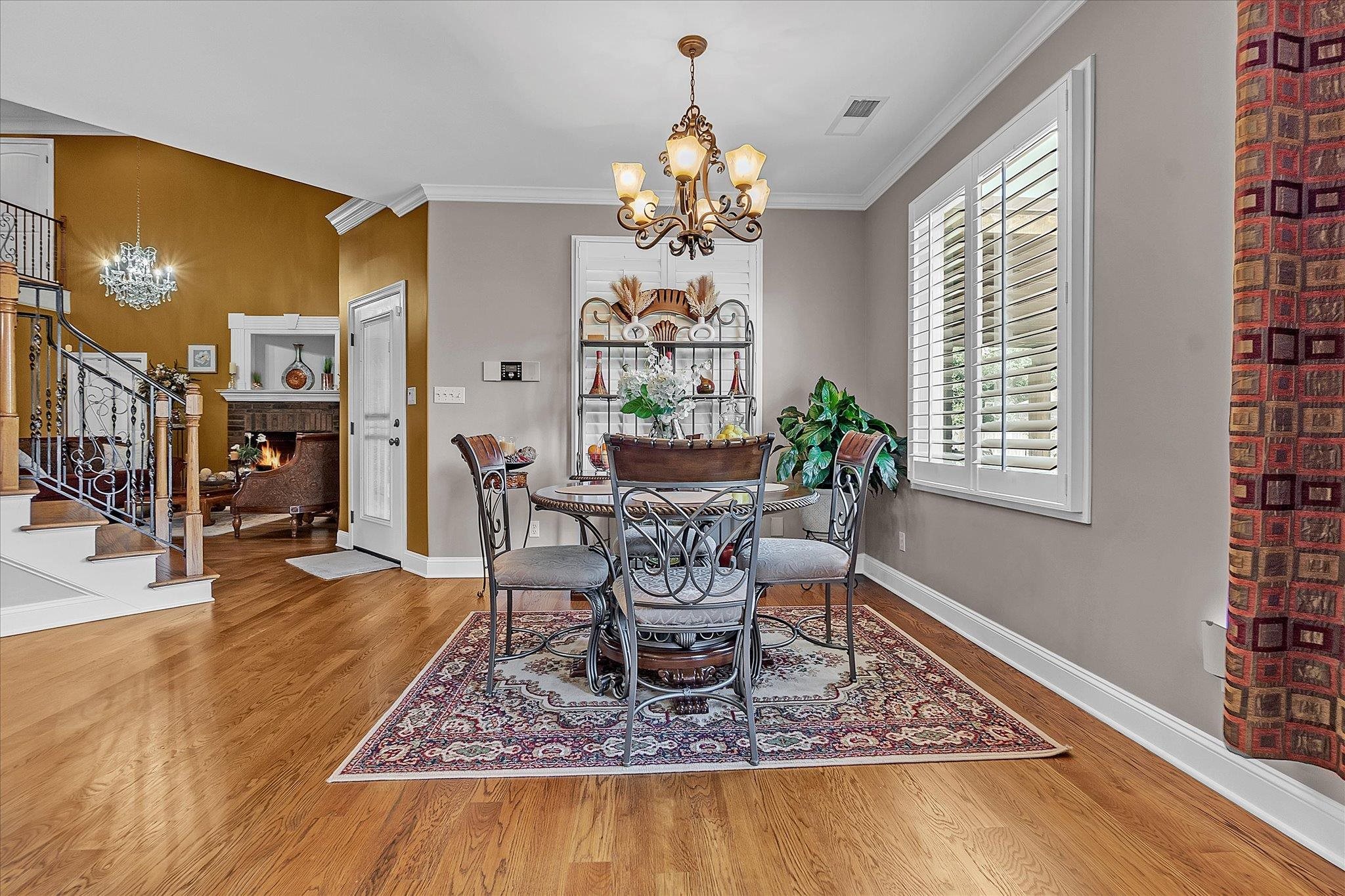 7284 Bucknell Road Millington, TN 38053 - Photo 19 of 35 Wood-finish flooring throughout, a decorative chandelier, white plantation shutters, and a traditional fireplace with mantel