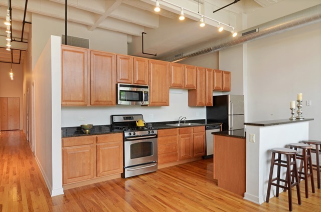 1224 West Van Buren Street, Unit 213 Chicago, IL 60607 - Photo 5 of 16 a kitchen with granite countertop a stove top oven a sink dishwasher a dining table and chairs with wooden floor