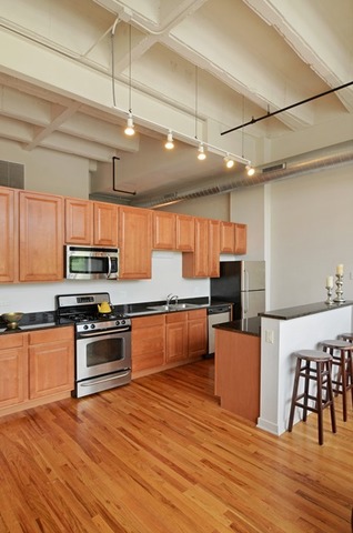 1224 West Van Buren Street, Unit 213 Chicago, IL 60607 - Photo 7 of 16 a large kitchen with stainless steel appliances granite countertop a stove and a wooden floors