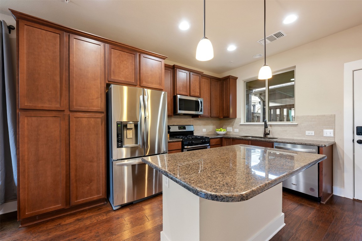 7615 Wolverine Street Austin, TX 78757 - Photo 11 of 40 a kitchen with stainless steel appliances granite countertop a refrigerator a sink dishwasher a oven with a dining table and chairs