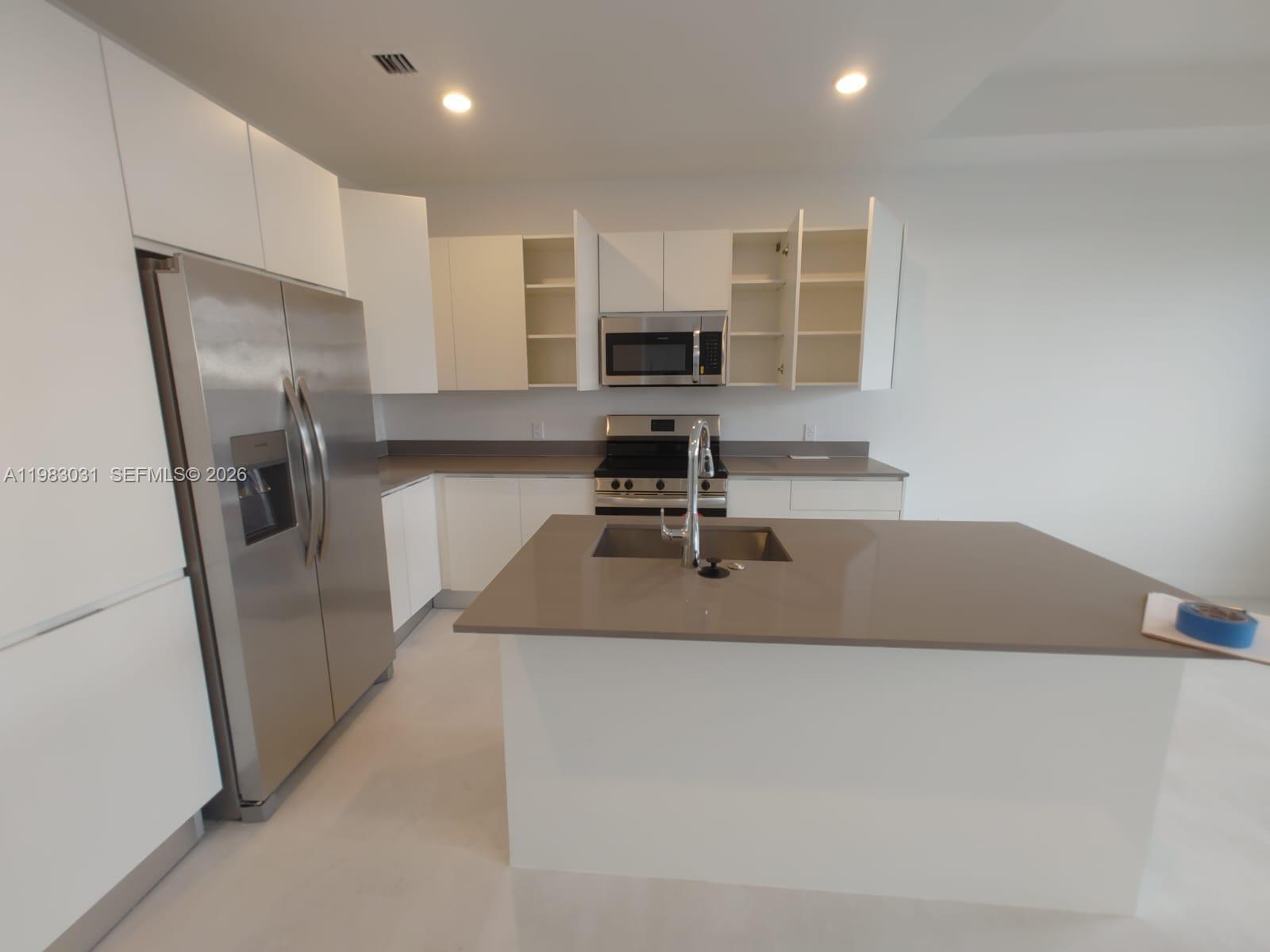 18983 Southwest 345th Terrace Homestead, FL 33034 - Photo 3 of 33 a kitchen with a refrigerator a sink a stove a microwave a counter top and cabinets