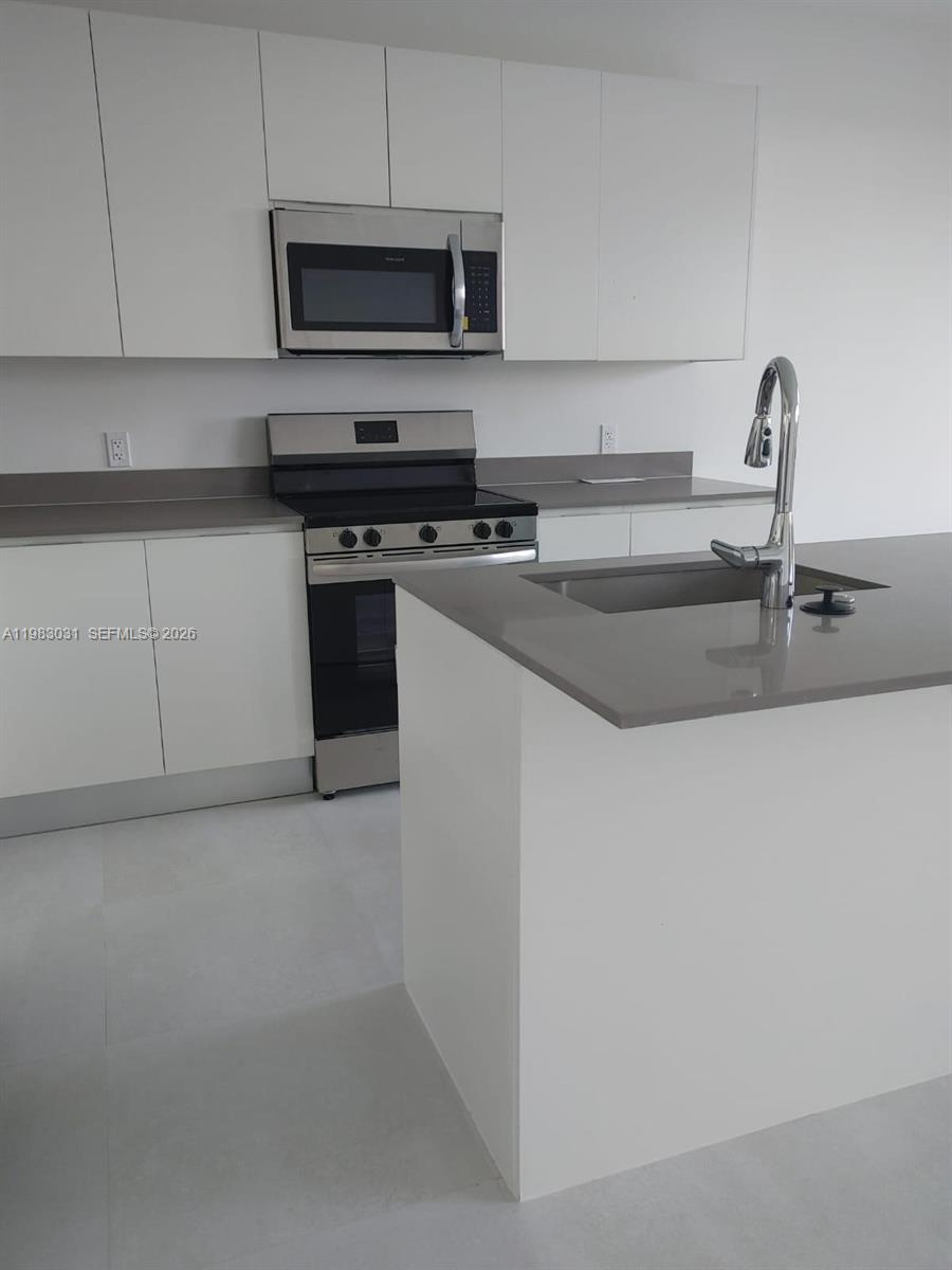 18983 Southwest 345th Terrace Homestead, FL 33034 - Photo 4 of 33 a kitchen with stainless steel appliances a sink a stove and a microwave