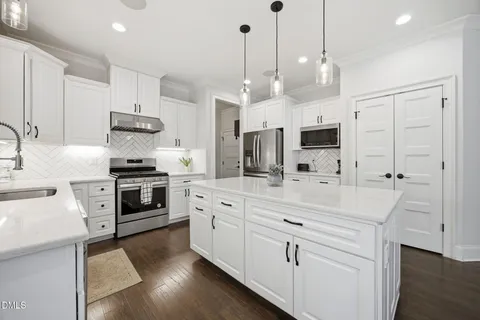 a large kitchen with white cabinets and stainless steel appliances