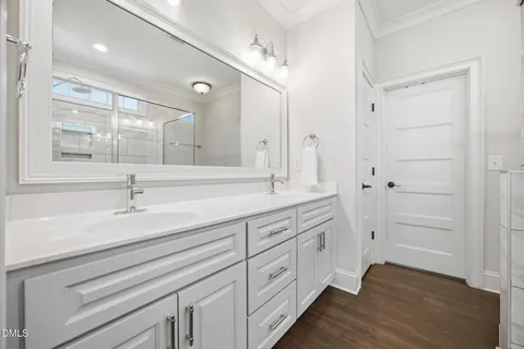 a spacious bathroom with a double vanity sink a mirror and shower