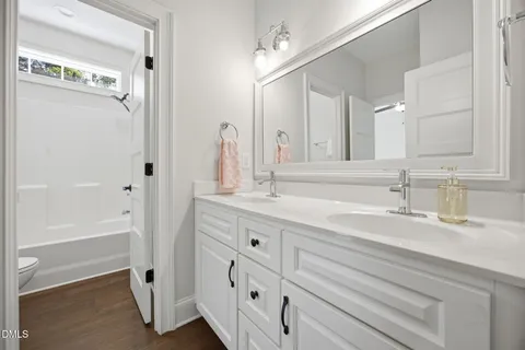 a bathroom with a double vanity sink a mirror and a bathtub