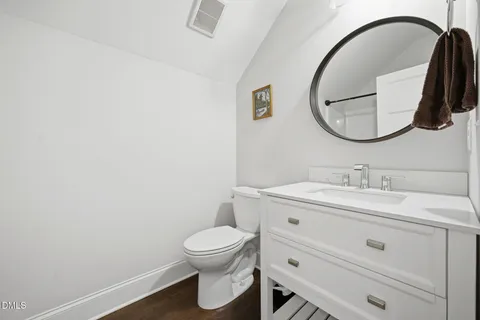 a bathroom with a toilet sink vanity and mirror