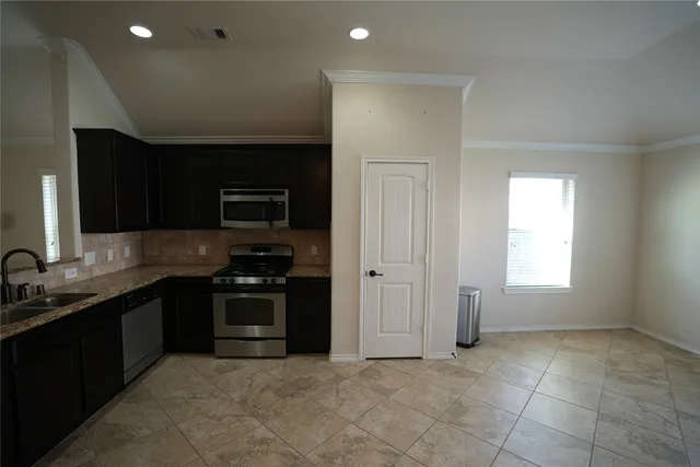 a kitchen with stainless steel appliances granite countertop a stove a sink and a microwave