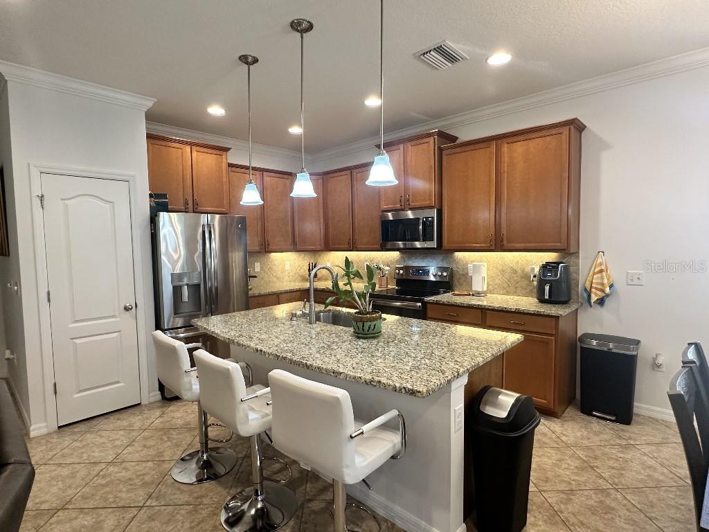 11248 Mollymawk Court New Port Richey, FL 34654 - Photo 11 of 21 a kitchen with stainless steel appliances granite countertop a table chairs sink refrigerator and microwave