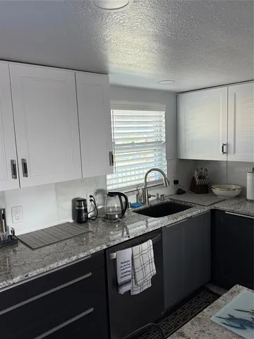 a kitchen with granite countertop a sink a stove and cabinets