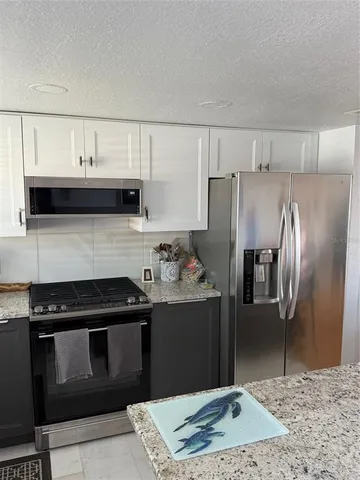 a kitchen with granite countertop a refrigerator stove and sink
