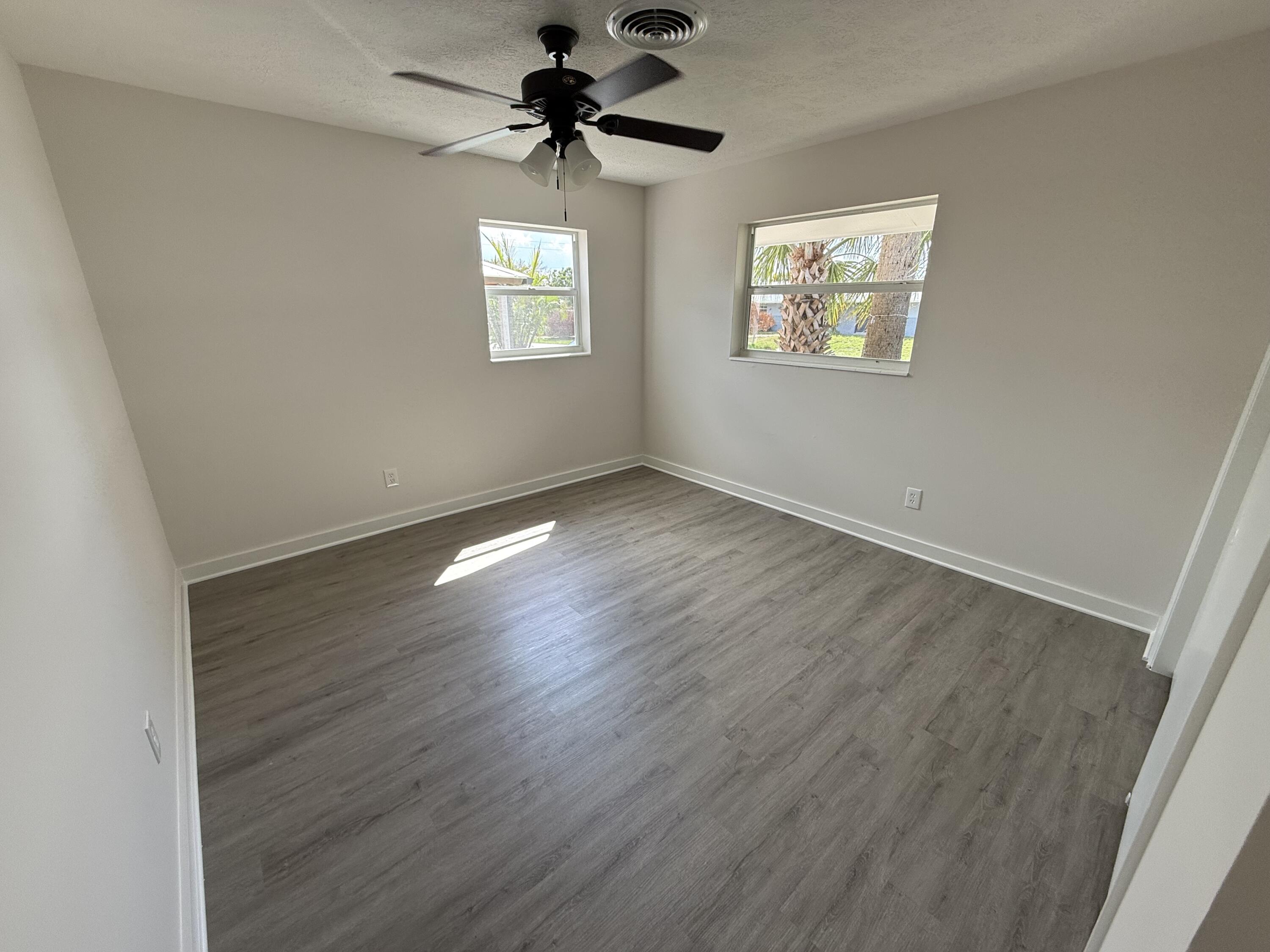 2369 Northeast Rustic Way Jensen Beach, FL 34957 - Photo 11 of 11 a view of an empty room with a window and wooden floor