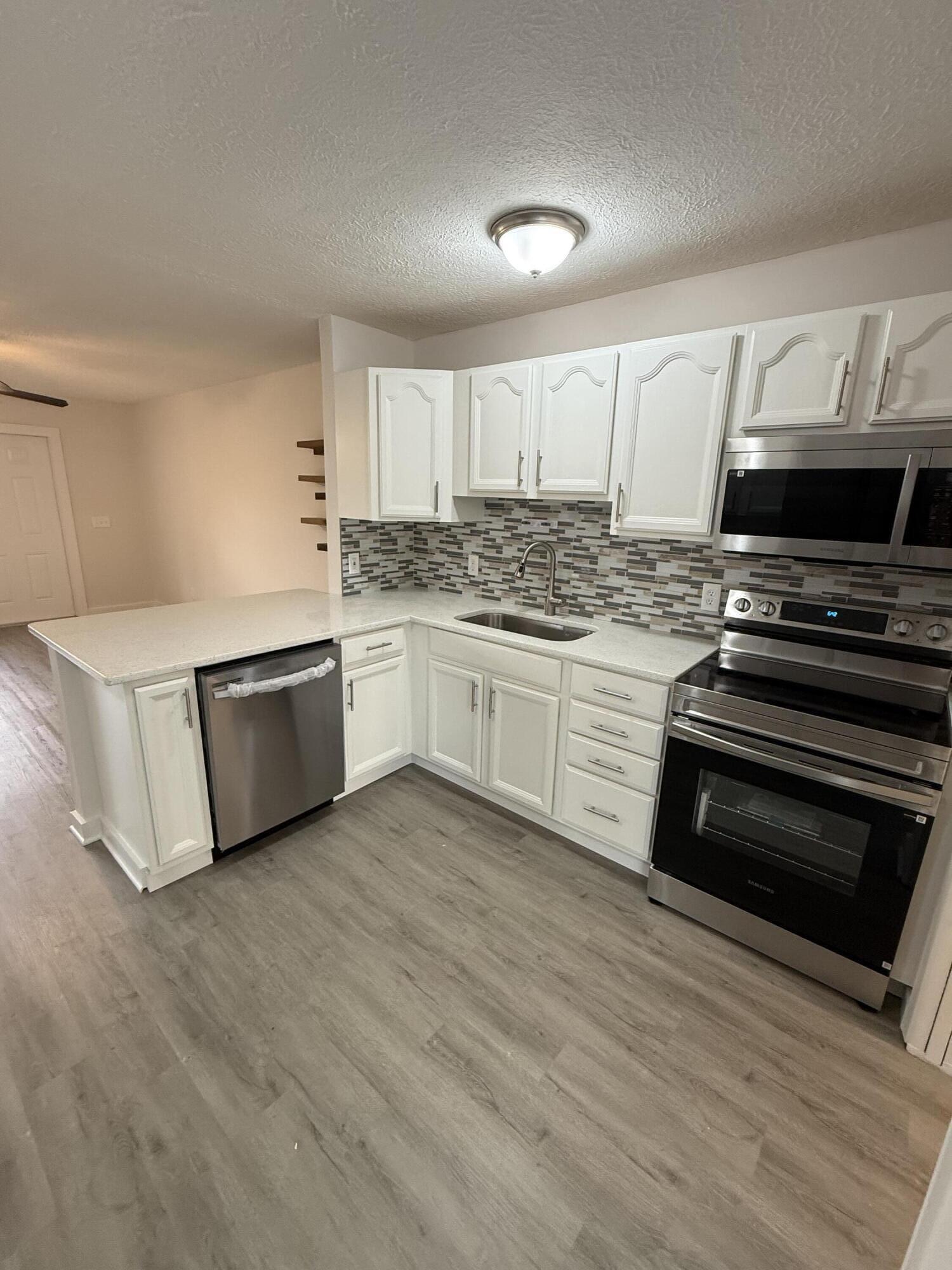 2369 Northeast Rustic Way Jensen Beach, FL 34957 - Photo 2 of 11 a kitchen with stainless steel appliances and wooden floor