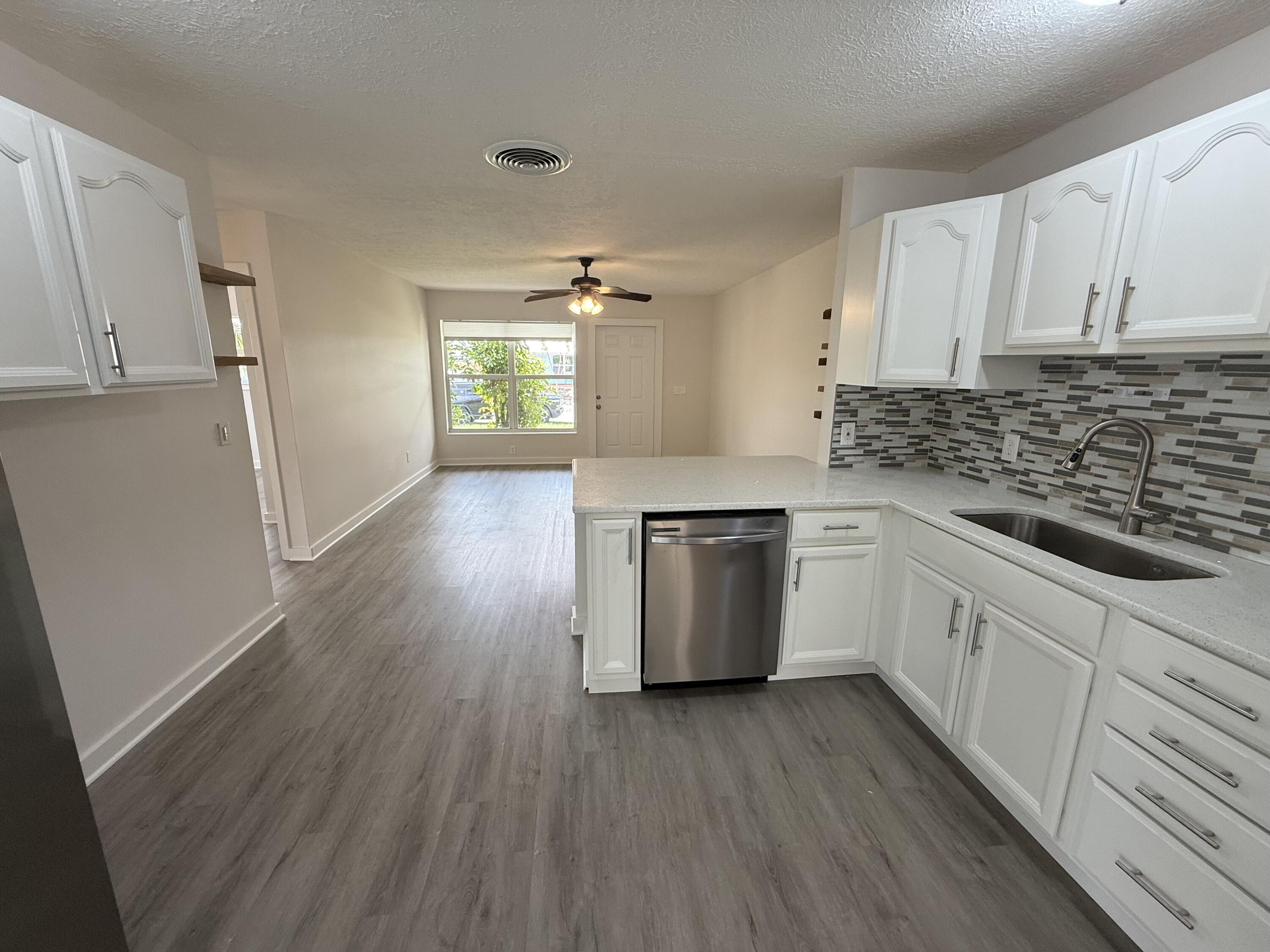 2369 Northeast Rustic Way Jensen Beach, FL 34957 - Photo 5 of 11 a kitchen with wooden floors and white appliances