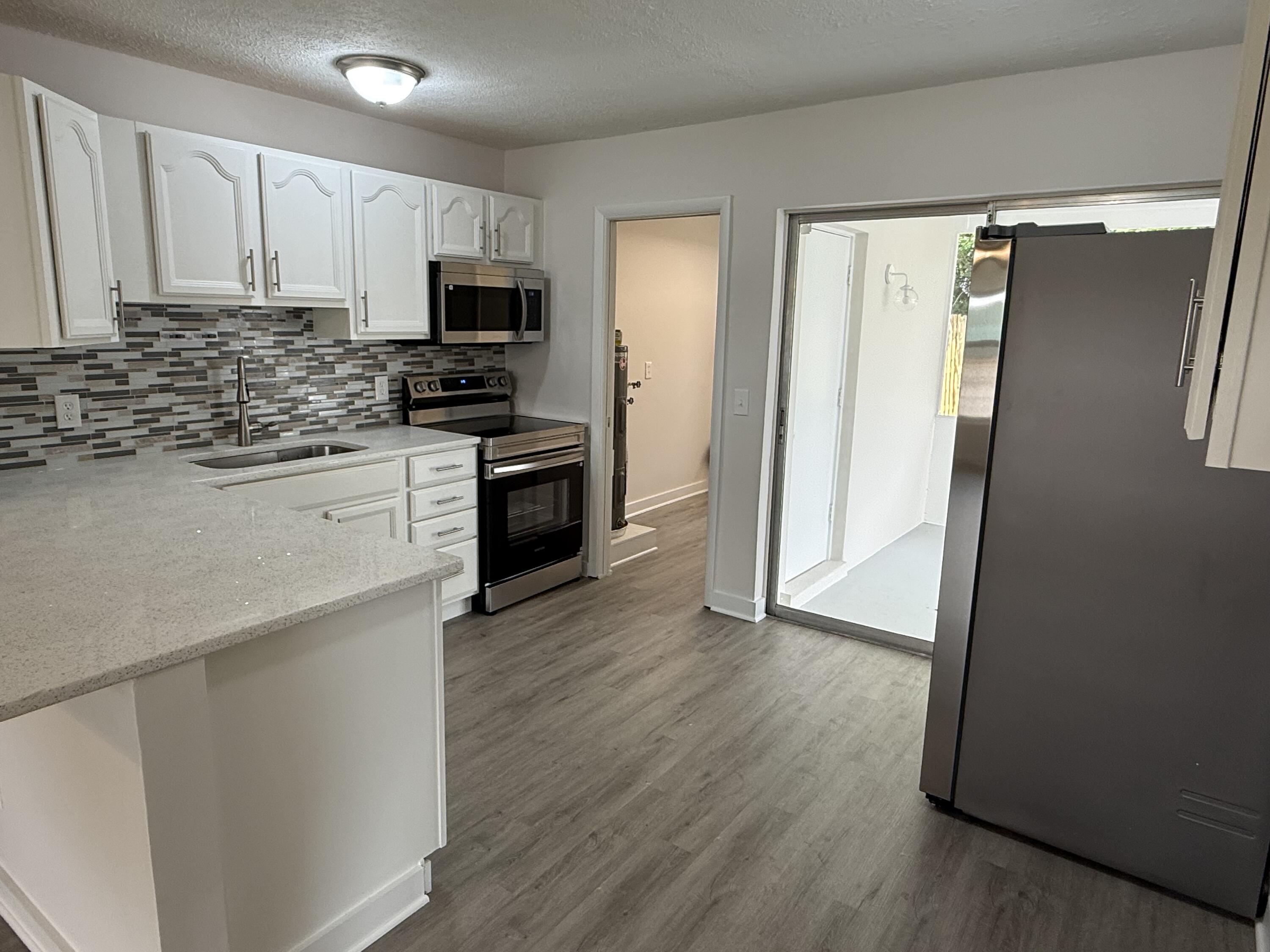 2369 Northeast Rustic Way Jensen Beach, FL 34957 - Photo 6 of 11 a kitchen with granite countertop a refrigerator stove and microwave