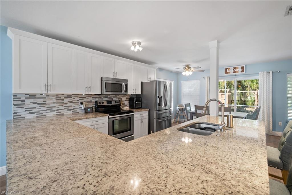 19034 Flamingo Road Fort Myers, FL 33967 - Photo 3 of 31 a kitchen with granite countertop a refrigerator and a stove top oven