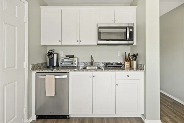 a kitchen with stainless steel appliances granite countertop white cabinets a sink and dishwasher