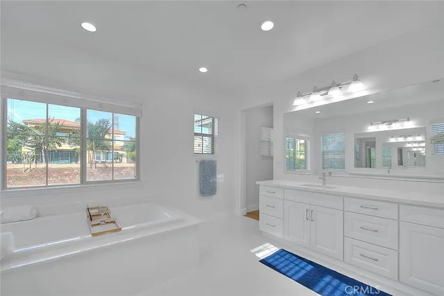 a bathroom with a tub a double vanity sink a window and a mirror