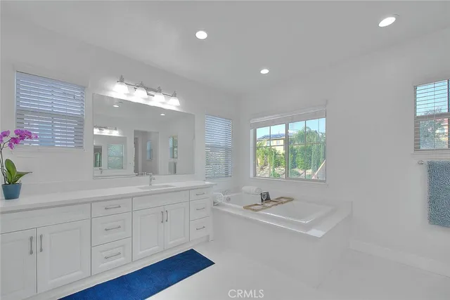 a bathroom with a sink double vanity granite tub and a mirror