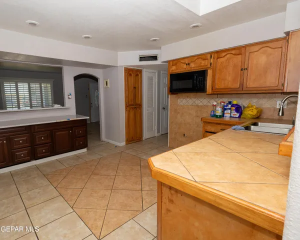 a room with stainless steel appliances kitchen island granite countertop a refrigerator and cabinets