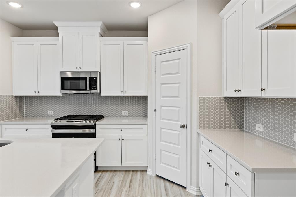 4149 Beale Street Heartland, TX 75114 - Photo 3 of 27 a kitchen with white cabinets and black appliances
