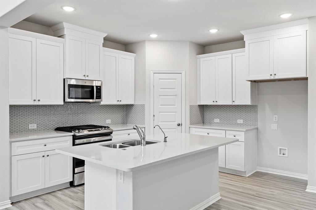 4149 Beale Street Heartland, TX 75114 - Photo 4 of 27 a kitchen with white cabinets and stainless steel appliances