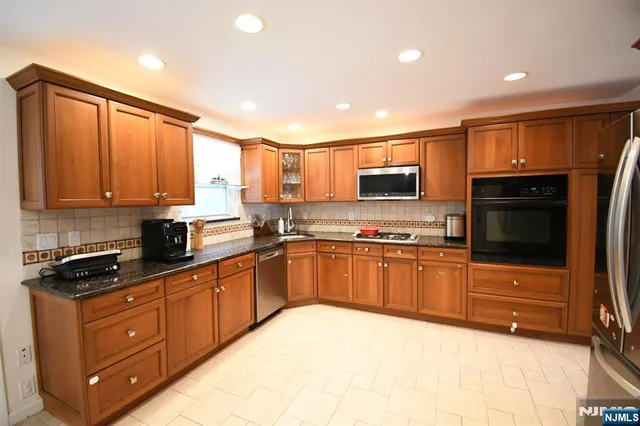 a kitchen with stainless steel appliances granite countertop a refrigerator stove microwave and sink
