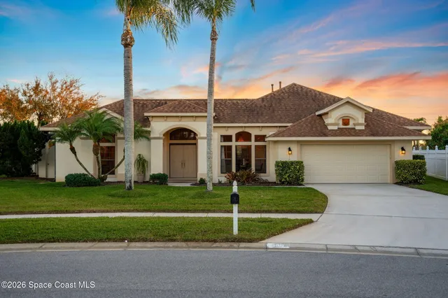 a view of a white house with a big yard and palm trees