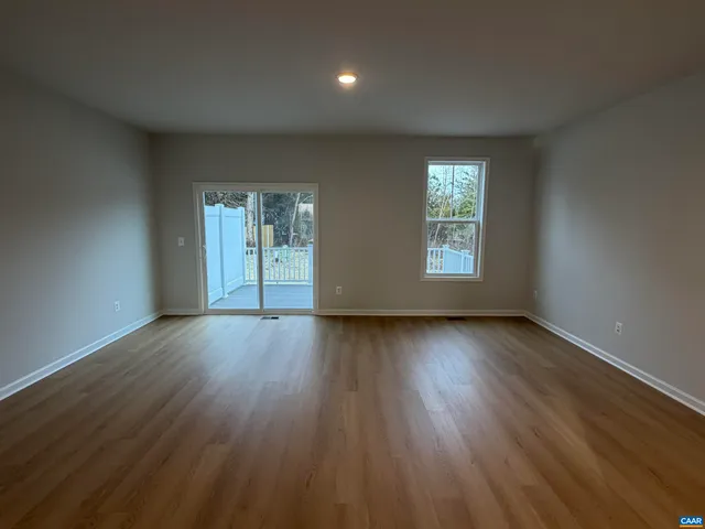 a view of an empty room with wooden floor and window
