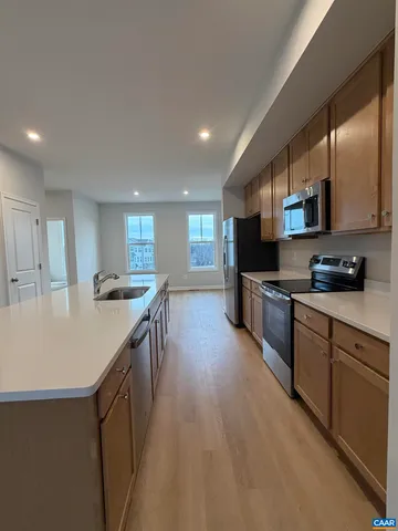 a kitchen with stainless steel appliances granite countertop a sink and a stove top oven with wooden floor