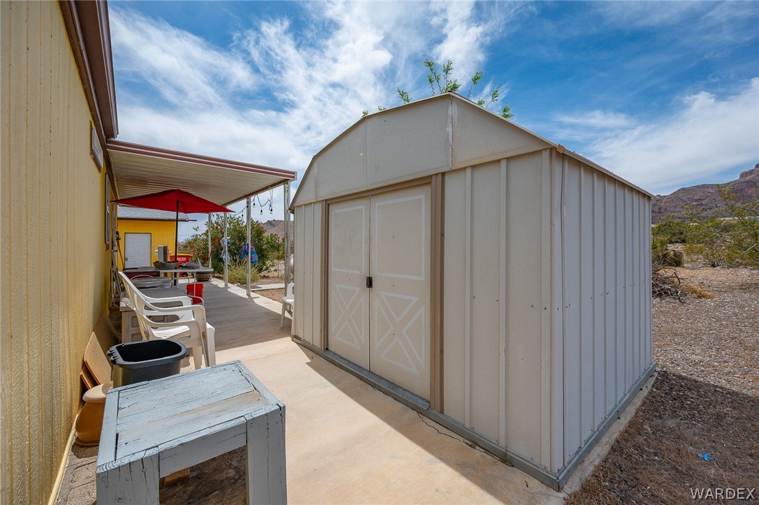 2465 Egar Road Golden Valley, AZ 86413 - Photo 52 of 98 The property features a useful storage shed with double doors, and a covered patio area with string lighting