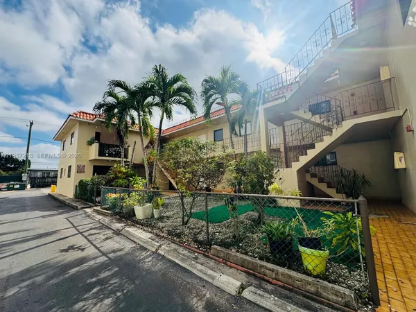 a front view of a house with lots of trees and flowers
