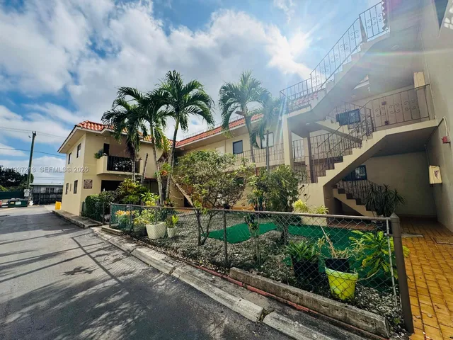 a front view of a house with lots of trees and flowers
