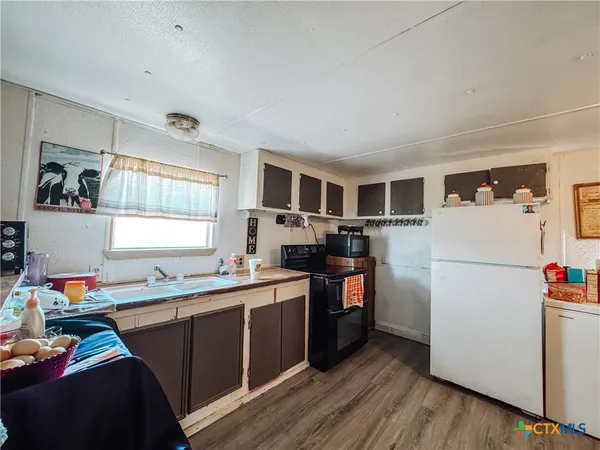 a kitchen with a refrigerator a stove top oven a sink dishwasher and a dining table with wooden floor