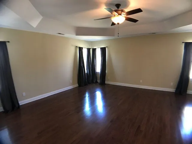 a view of an empty room with window and wooden floor