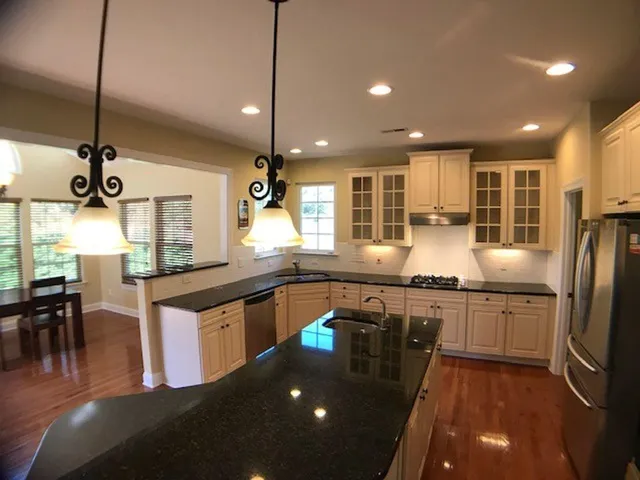 a kitchen with stainless steel appliances granite countertop a sink a stove and a wooden floor