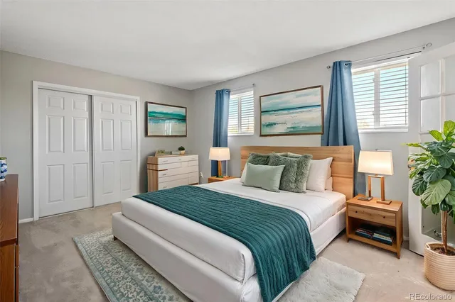 a spacious bedroom with a bed a couch and potted plant